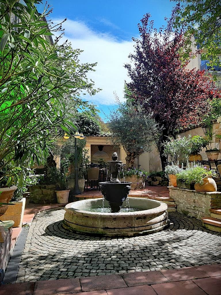 Der mediterrane Gartenbrunnen von Henri Studio im Mittelpunkt der Gästeterrasse mit südlichem Flair